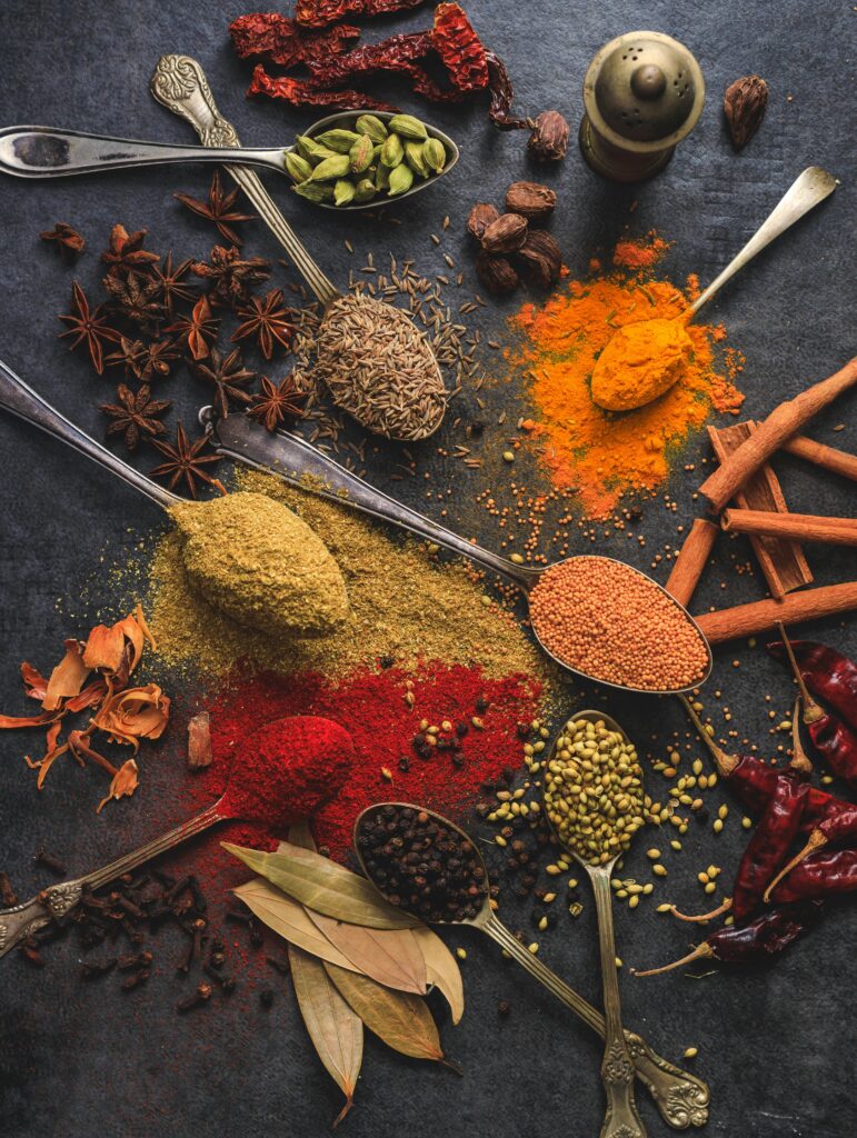 Vibrant array of spices including turmeric, cumin, and chili arranged on a dark surface.