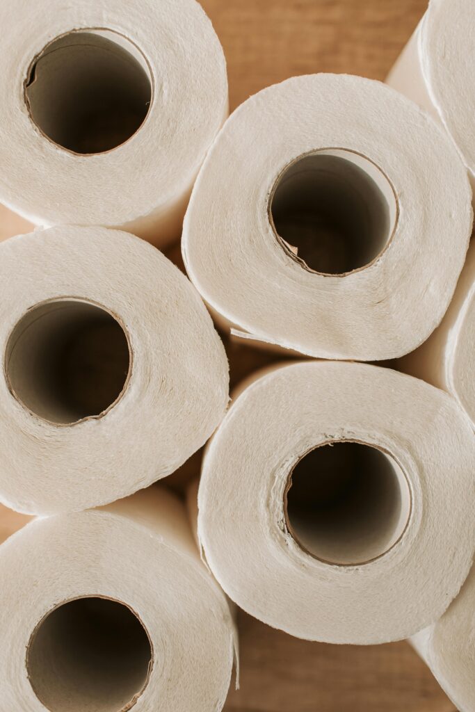 Top view of multiple toilet paper rolls arranged on a wooden surface, offering ample copy space.